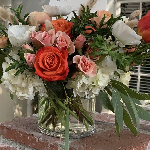 Orange and pink roses with white hydrangeas in glass vase from custom floral design Raleigh