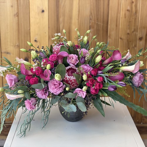 Lavender roses and pink calla lilies with protea in dark vessel for Raleigh flower arrangements
